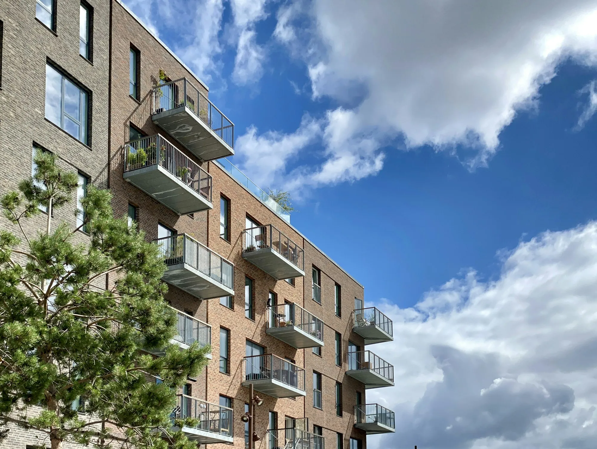 Brick apartment building with balconies under a blue sky