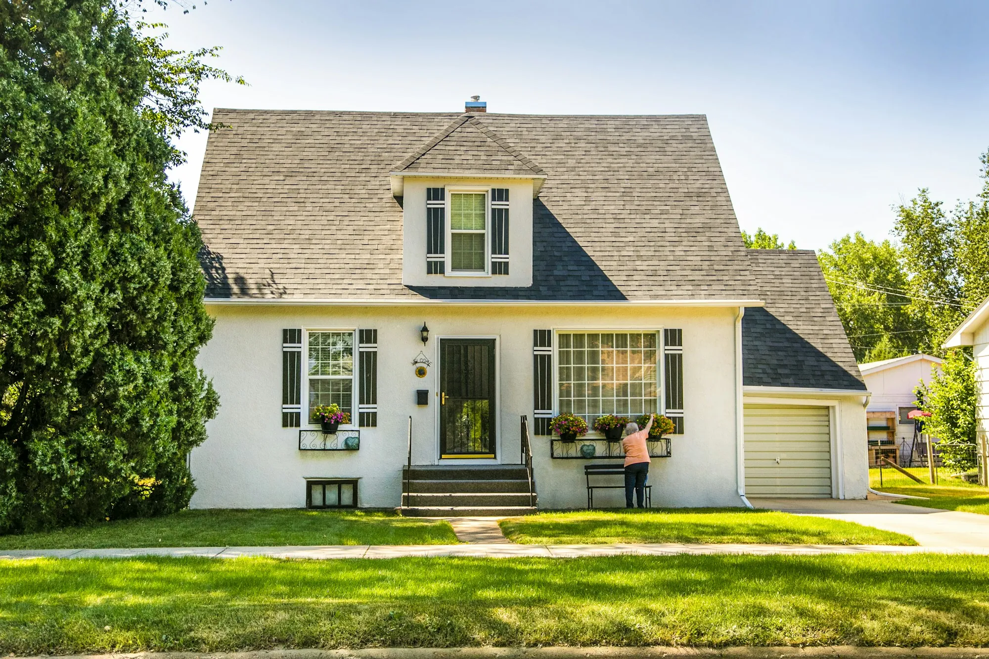 White cottage-style house with dormers and a front lawn